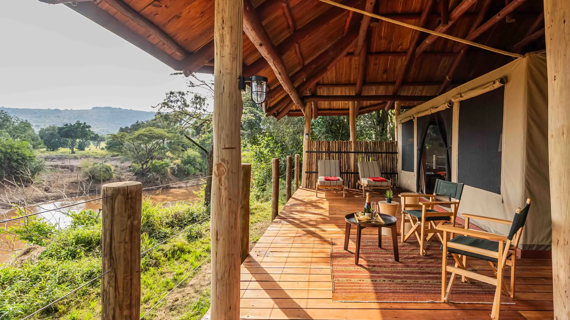 The private deck of a river suite, chairs looking out over the Mara River and the plains beyond