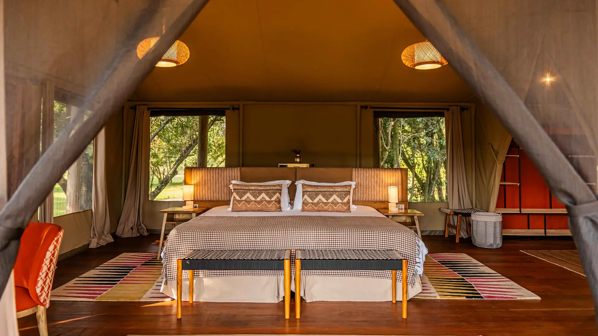 Twin beds beneath the high canvas roof of a river suite